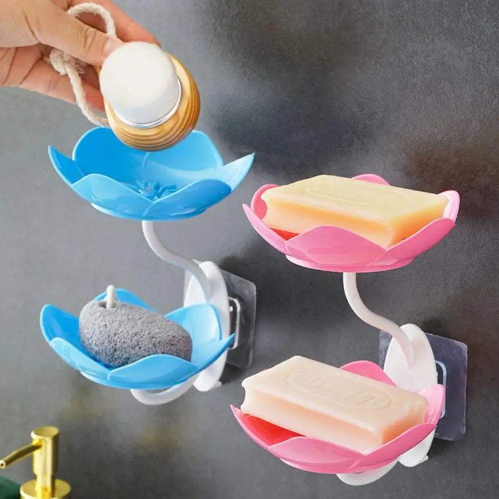 A hand is holding a white soap dispenser, which is attached to a two-tier bathroom storage rack with drainage.
