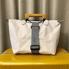 A white reusable elastic luggage strap with a leather handle is displayed on a yellow surface.