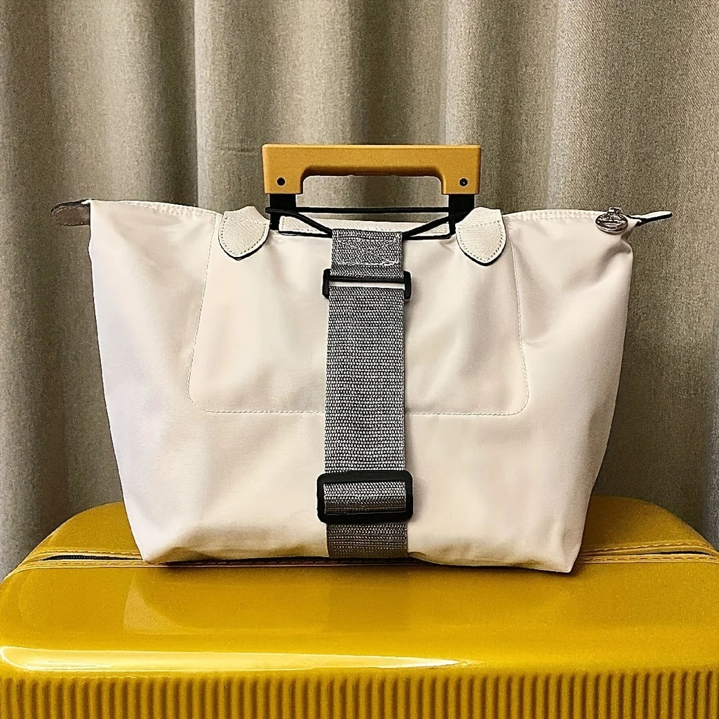 A white reusable elastic luggage strap with a leather handle is displayed on a yellow surface.