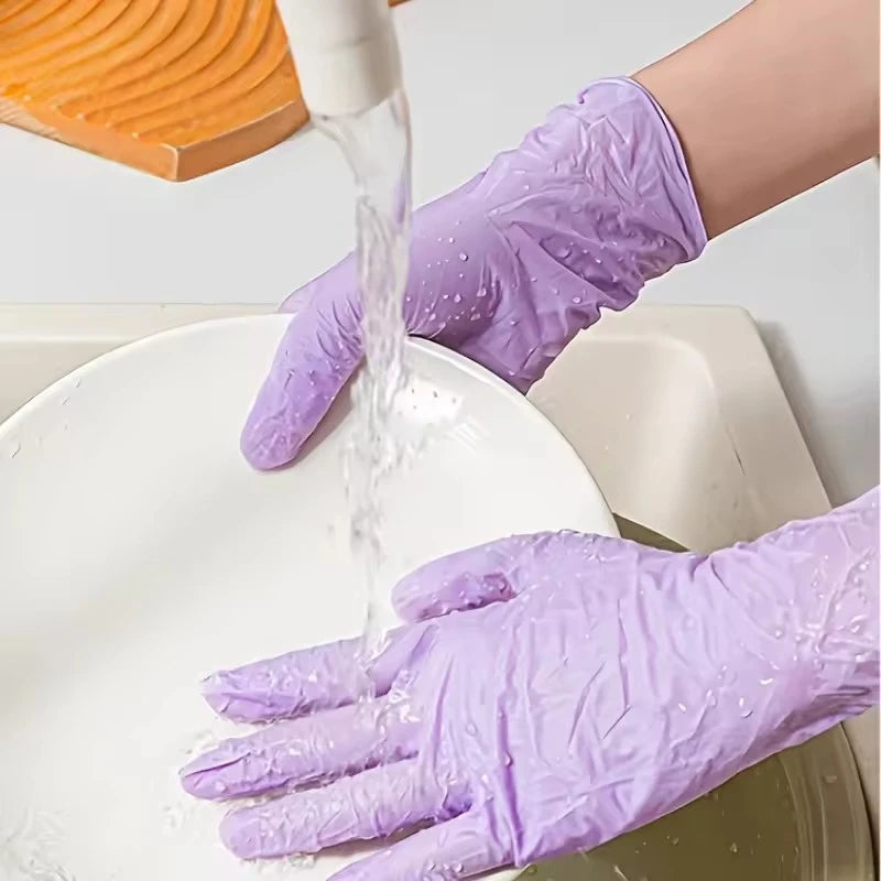 A hand wearing a light purple disposable nitrile glove is pouring liquid onto a white plate.