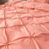 A close-up of a pink satin pinch pleated duvet cover set with quilted texture.
