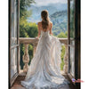 A woman with long hair stands looking out of a window at a scenic landscape wearing a white diamond painting dress.