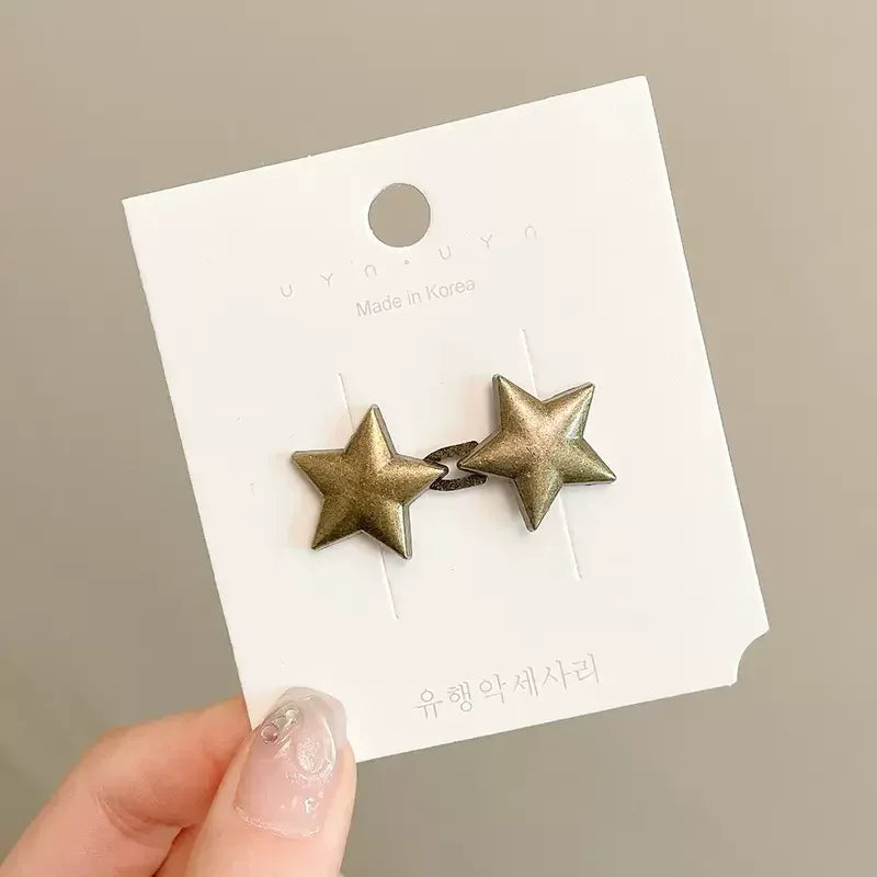 A gold-toned star-shaped metal brooch or belt buckle is displayed on a white product tag.