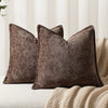 A dark brown textured chenille decorative cushion cover square throw pillow resting on a cream knitted blanket.