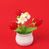 Handcrafted crochet sunflower with red and white petals growing in a small white pot
