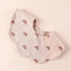 A light beige cotton baby bib with a repeating rainbow pattern shown from above.