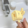 A yellow rabbit-themed anti-splash faucet extender is shown being held by a hand next to a glass and a white bottle.