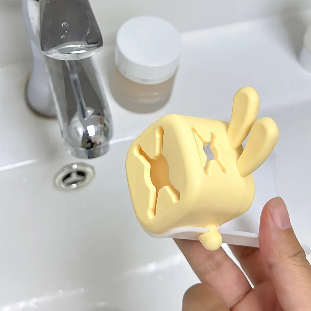 A yellow rabbit-themed anti-splash faucet extender is shown being held by a hand next to a glass and a white bottle.