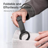 A hand is holding a black magnetic phone tripod with a carabiner clip, demonstrating its portable design.