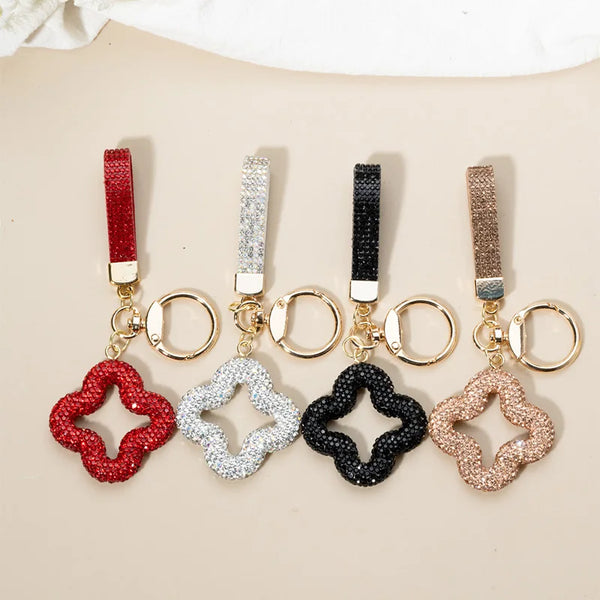 Five rhinestone clover keychains in red, silver, black, gold, and rose gold tones