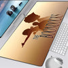 A close-up of a large, tan gaming mouse pad with the title The Boondocks printed on it, next to a laptop and a mouse.