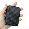 A hand holds a black plaid compact utility pouch made of premium Dyneema and X-Pac materials.