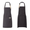 A dark gray waterproof canvas chef apron with wooden toggles and a gathered waist.