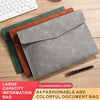 Une pile de quatre pochettes en cuir personnalisables dans des tons de vert, brun et gris avec un stylo noir.