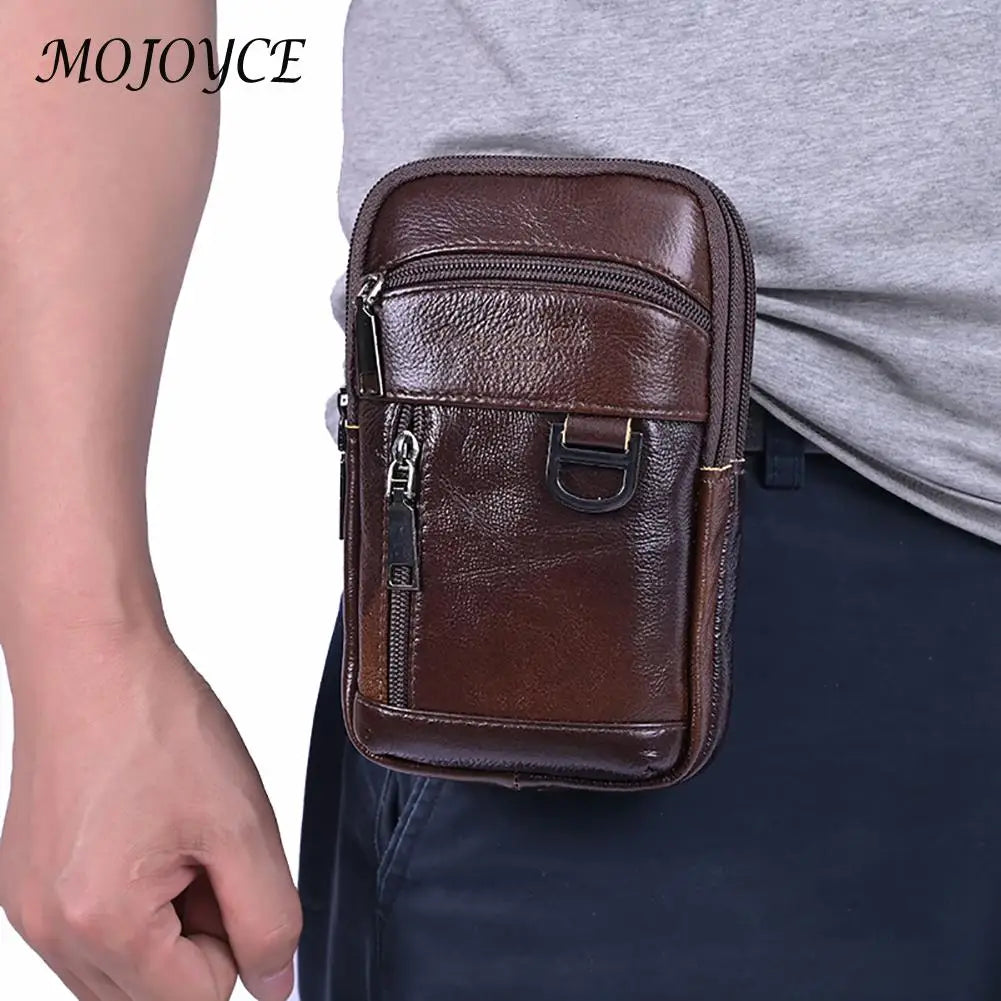 A brown genuine cowhide leather crossbody sling bag is shown being held by a person against a gray shirt and dark pants.