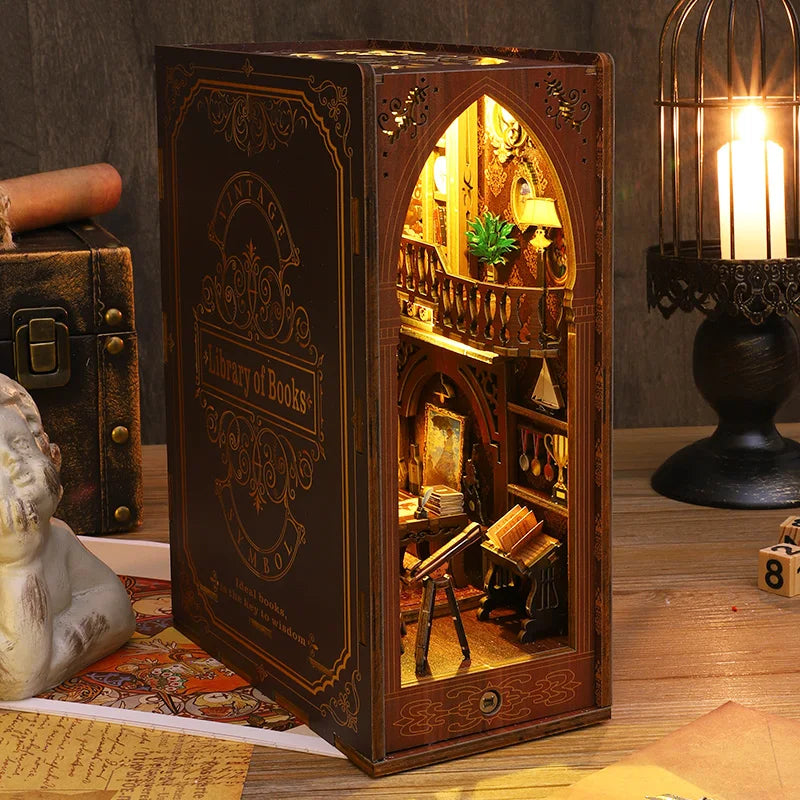 A dark wooden book nook kit featuring an arched interior with detailed miniature scenes and warm lighting.