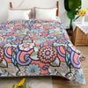 A colorful patchwork cotton bedspread featuring floral and paisley patterns in pink, purple, blue, and green.
