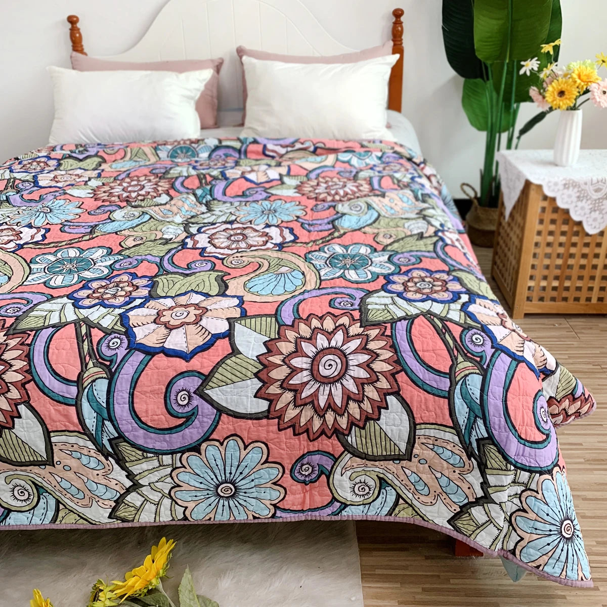 A colorful patchwork cotton bedspread featuring floral and paisley patterns in pink, purple, blue, and green.
