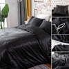 Black silky duvet cover set featuring corner ties and a zipper on a bed.
