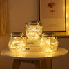 Three glass solar lanterns with warm ambient glow resting on a wooden surface.