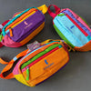 Three colorful unisex water-resistant crossbody chest bags in purple, orange, and blue fabric