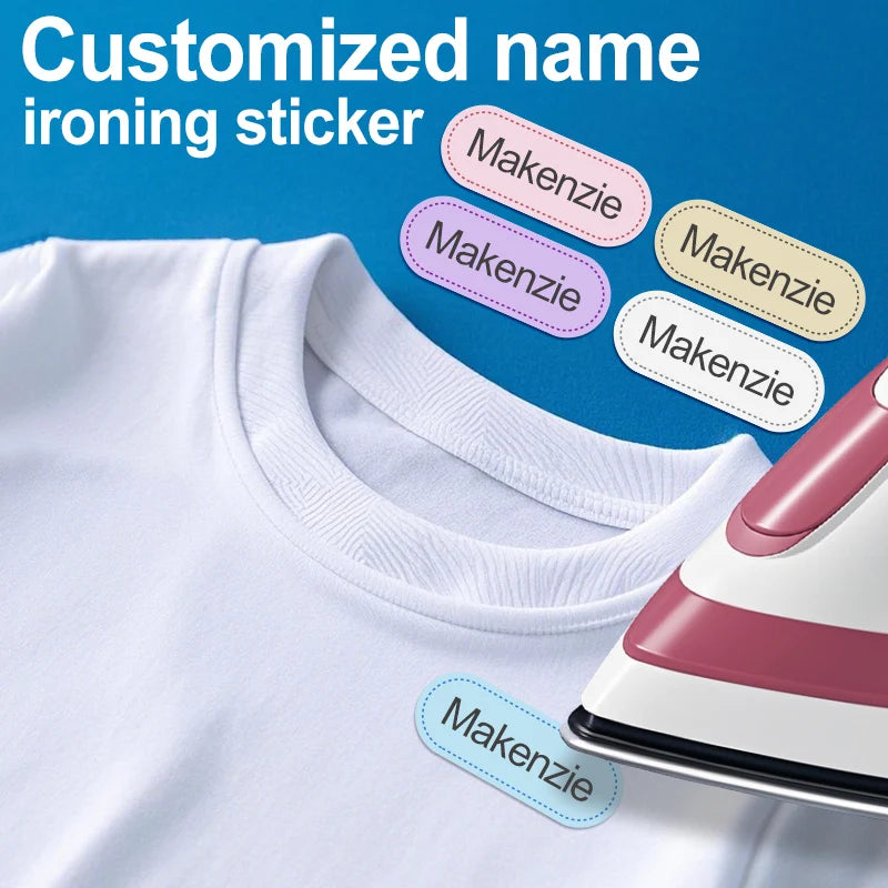 Una camiseta blanca con varias pegatinas de nombre para planchar en tonos rosa y morado, incluyendo el nombre Mackenzie.