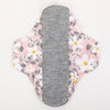 Reusable cotton menstrual pads in pink floral pattern with a gray absorbent core.