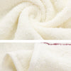 A close-up of a white, fluffy bath towel set being rolled or draped.
