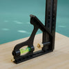 A black multifunctional carpenter square with an angle level and protractor resting on a wooden surface.