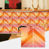 Orange and pink herringbone marble peel-and-stick wall tiles installed on a wooden shelf.