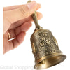 A hand is holding a vintage brass hand bell with an ornate design.