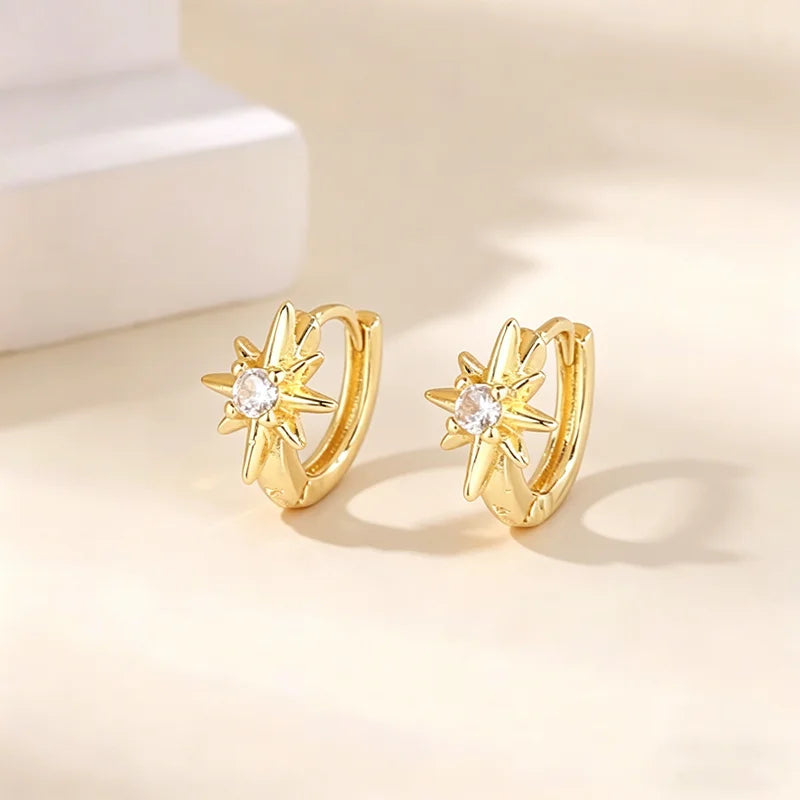 Par de aretes de aro dorados con diseño de estrella y piedra de circonita cúbica.