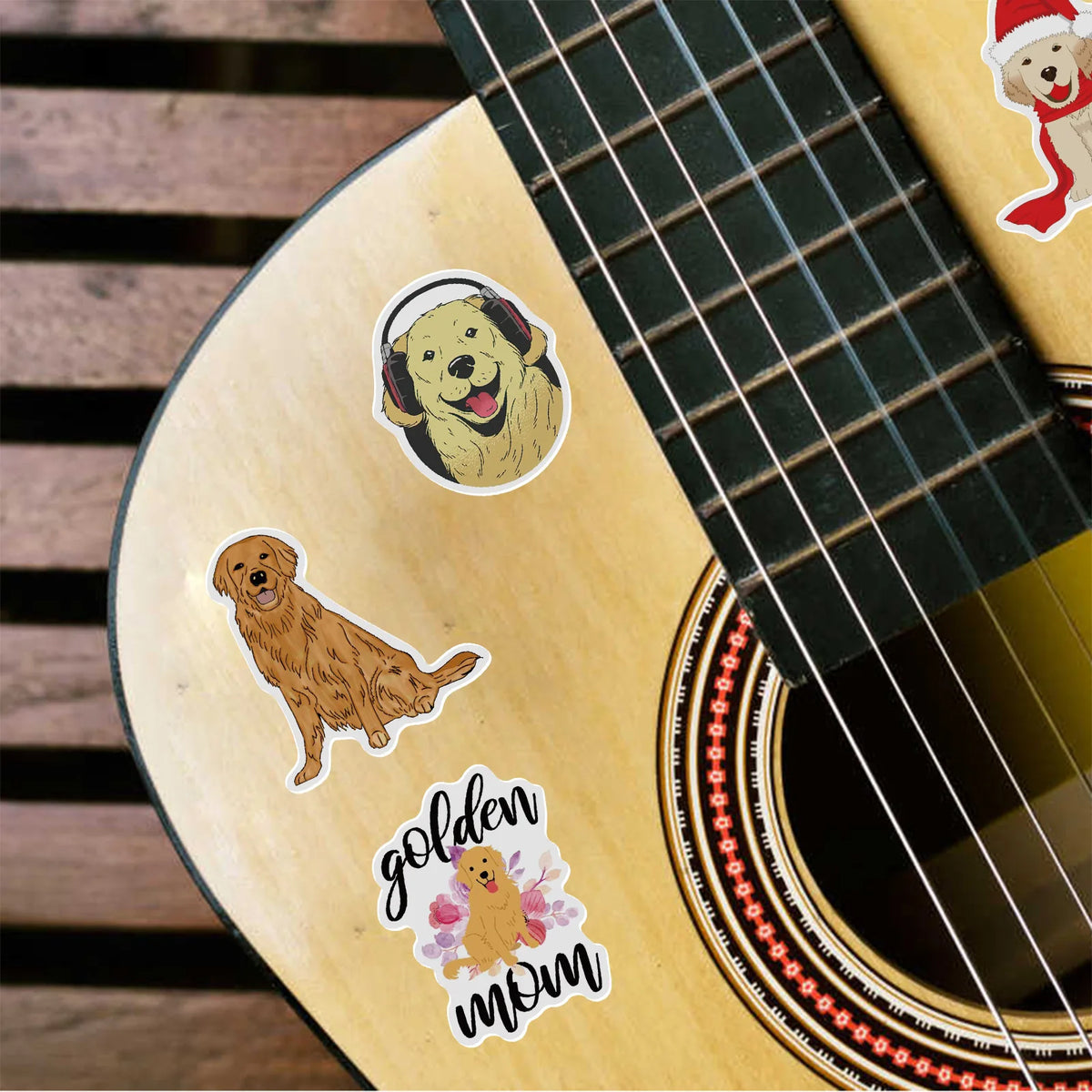Close-up of a guitar body featuring stickers of golden retrievers and the text golden mom