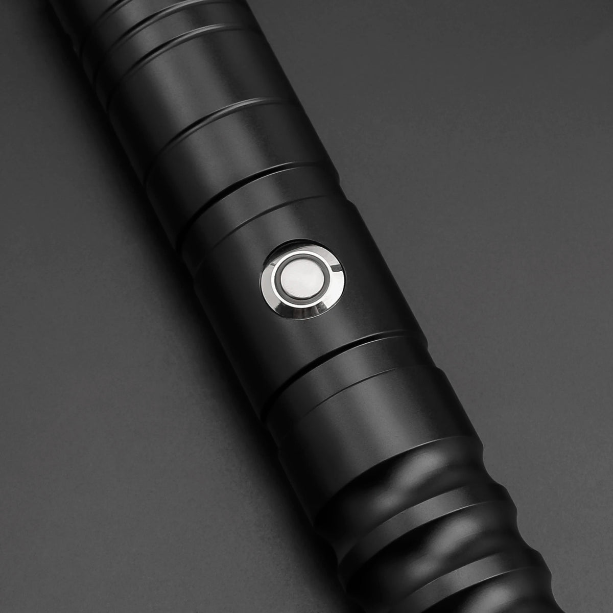 Close-up view of a black lightsaber hilt with a circular metallic light emitter.