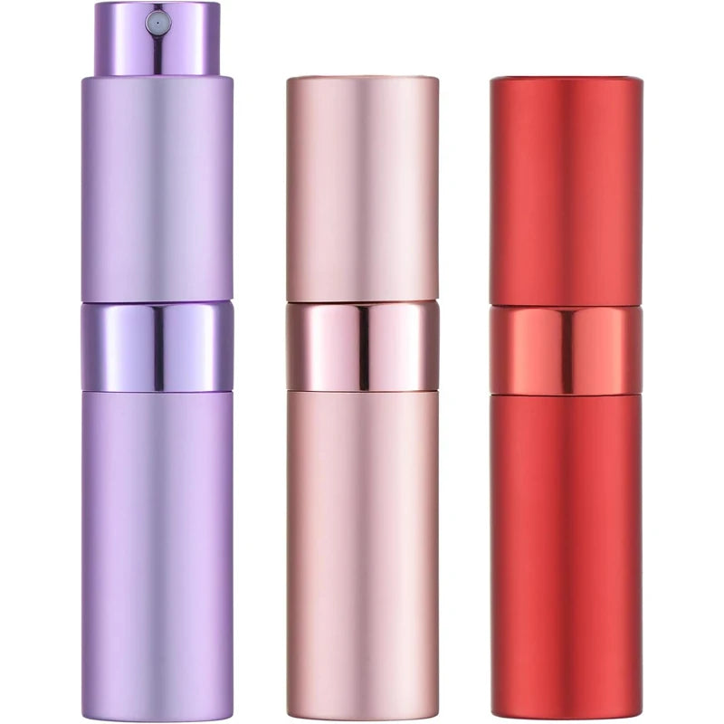 Un set de tres atomizadores de perfume cilíndricos en morado, oro rosado y rojo.