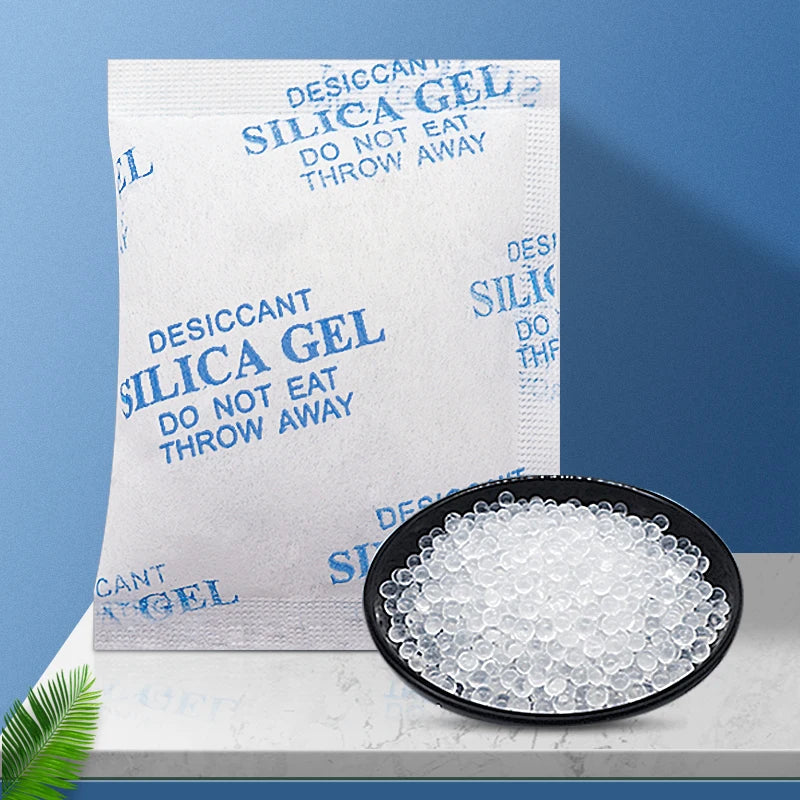 A white silica gel desiccant bag is shown next to a black dish filled with white silica gel beads.