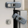 Close-up of a clear plastic child safety cabinet lock mechanism on a refrigerator door.