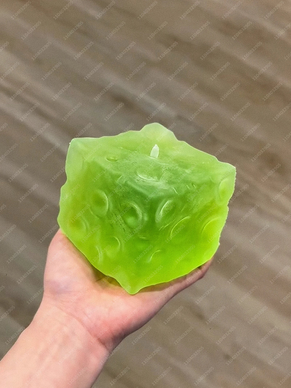 A hand holds a bright green frosted matte jumbo cheese stress ball against a neutral background.