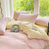 A pink and cream striped duvet cover set with two pillows on a bed near a large window overlooking greenery.