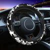 A black steering wheel covered with a white and gray camouflage pattern in a car interior.