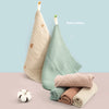 A stack of light green and beige pure cotton gauze burp cloths for babies.
