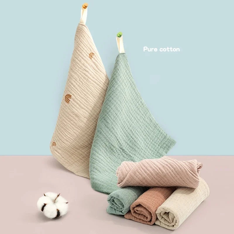 A stack of light green and beige pure cotton gauze burp cloths for babies.