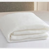 White folded quilt or blanket showing soft, fluffy texture on a white surface.