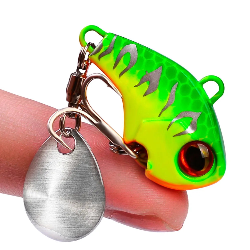 A silver metal spinner fishing lure attached to a bright green plastic hook on a finger.