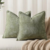 A moss green chenille decorative cushion cover square throw pillow resting on a beige textured fabric.