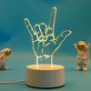 A glowing hand gesture sign is displayed on a white base, with a small astronaut figure in the background.
