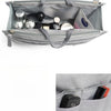 A gray purse organizer insert with multiple compartments holding various small items like makeup and accessories.