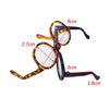 A pair of transparent plastic sunglasses with black frames and yellow-patterned lenses.