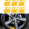 A close-up of a black car wheel with yellow reflective safety stickers on the rim.