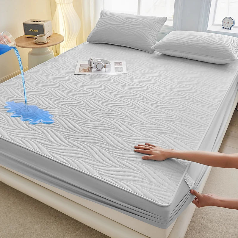 A white fitted mattress protector is shown on a bed, with a hand touching the fabric and water dripping onto it.